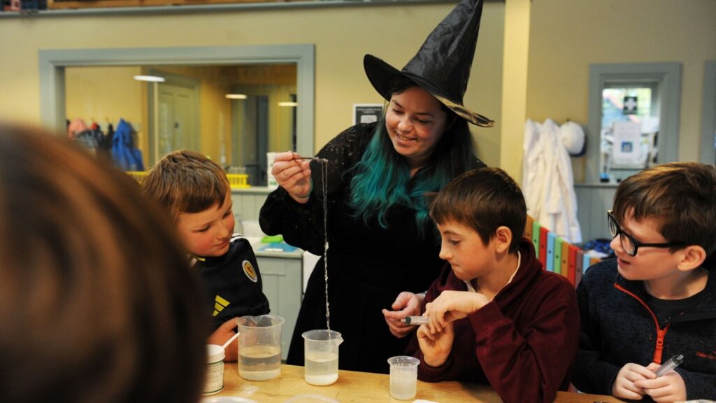 Photograph of a teacher dressed as a witch brewing educational potions in the STEM centre